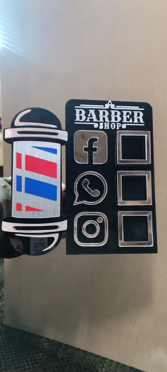 Display para barbería en acrílico negro con íconos de Facebook, WhatsApp e Instagram en acrílico espejo plateado, acompañado de un poste de barbero decorativo.