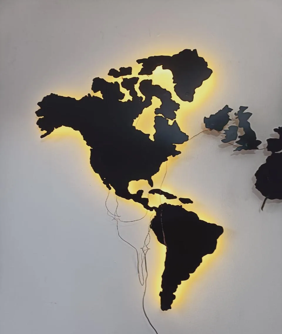 Mapamundi decorativo de pared cortado en madera con iluminación LED cálida indirecta detrás de los continentes.